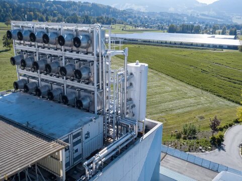 An industrial carbon capture facility installed in an open rural area, featuring large modular units designed to extract carbon dioxide directly from the air.