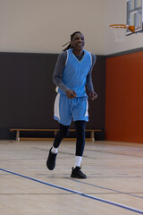 Obraz premium Basketball hoop and backboard are hanging on orange wall above hardwood court, bench visible