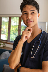 Asian doctor standing in navy scrubs checking smartwatch and sporting stethoscope in clinic lounge