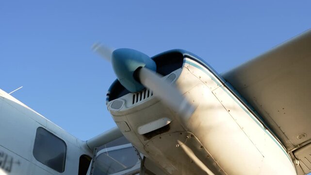 Close-up of a blue nose cone and propeller of a light aircraft in flight.