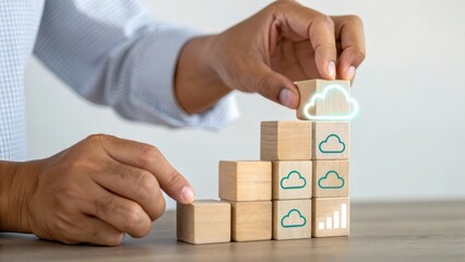 A person stacking wooden blocks featuring cloud icons, symbolizing growth and technology in a modern workspace.
