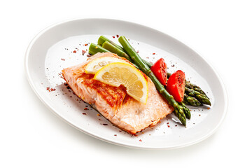 Garnished fried salmon steak with boiled green asparagus on white background