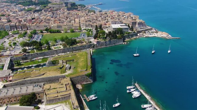 Aerial drone view of Corfu's Old Town, Greece, flying over the Old Fortress (Palaio Frourio), Spianada Square, and the historic city harbor with yachts