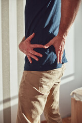 Man with hip, back, spine and sciatica pain at home.