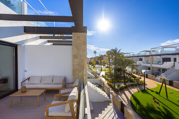 Modern apartment balcony overlooking tropical courtyard and playground in bright daylight