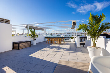 Fototapeta premium Contemporary rooftop terrace with pergola and potted palms in bright urban residential setting