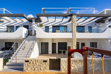 Contemporary white apartment building with terraces and stone accents in tropical urban setting