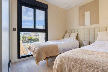 Bright twin bedroom with large window, neutral bedding and modern decor in minimalist style