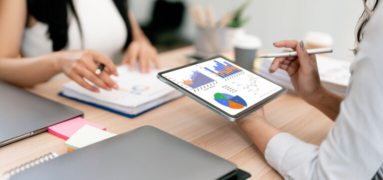Close-up of business professionals analyzing financial data and growth charts on a digital tablet during a meeting in a modern office.