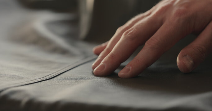closeup man hand checking seam on soft gray leather clothes