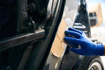 Repairman using putty to the car in auto repair shop