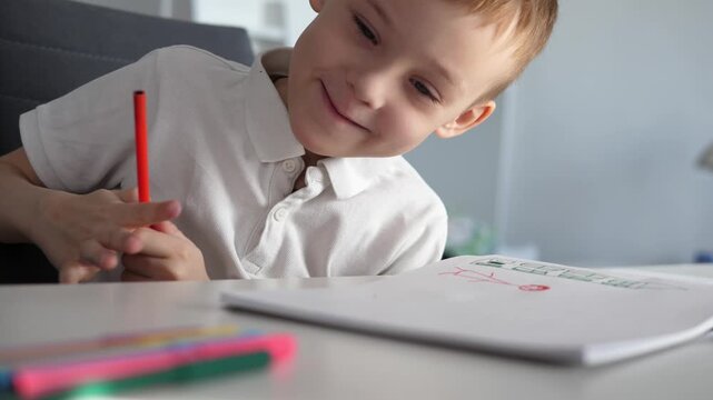 Close-up of a young boy writing or drawing with a pencil at a desk at home or school. Child focused on learning and doing homework. Concept of education, childhood development, concentration