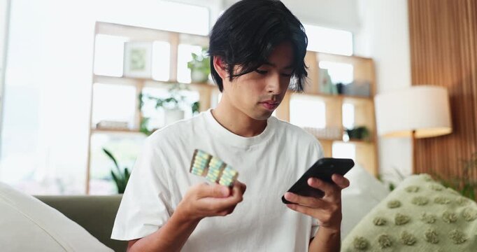 Home, pills and man on sofa, smartphone and reading label with prescription, internet and info. Apartment, mobile user and Asian person on couch, cellphone and app for medicine and health benefits