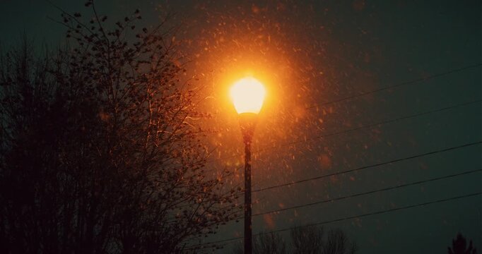 Static Shot of Lone Street Light Glowing Orange Against the Night Sky while Snow Falls During Midwest Winter