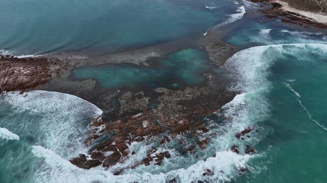 Aerial establishing of foamy whitewash waves and rugged rocks along the Salmon Hole coastline, Daly head natural pools