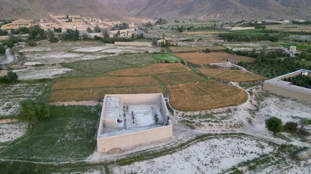 A striking sight of a mud house nestled amidst plentiful greenery in Paktia Province, Afhganistan, drone aerial of natural building materials construction