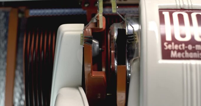 Close-up of a vintage jukebox mechanism carriage moving up and down, mechanical record changer detail.