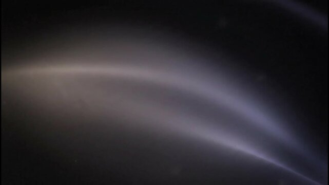 Celestial comet streaks across starless void in dramatic side angle astrophotography shot