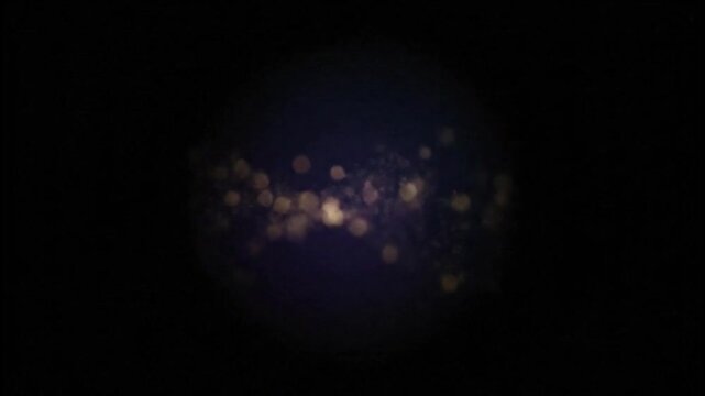 Blurry yellowish-white lights cluster mysteriously in center of dark low-key abstract night photo