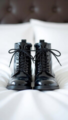 Pair of stylish black leather boots tied together on a clean white bed