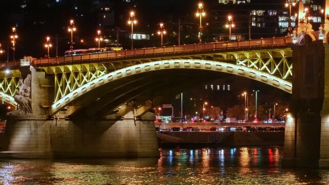 Stunning night view of the illuminated Margaret Bridge in Budapest, Hungary. The golden lights reflect beautifully on the Danube River surface, showcasing European architecture and city travel
