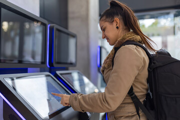 Young woman using interactive self-service touchscreen kiosk