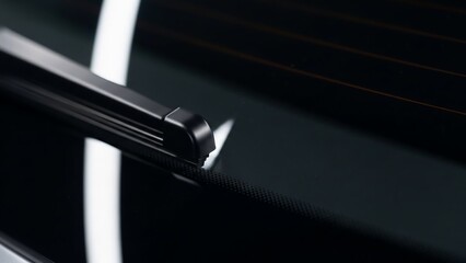Close-up of a sleek black metal hinge on a dark background.