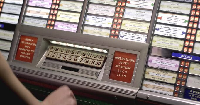Selecting a song on a vintage 1950s jukebox keypad, retro close-up detail.