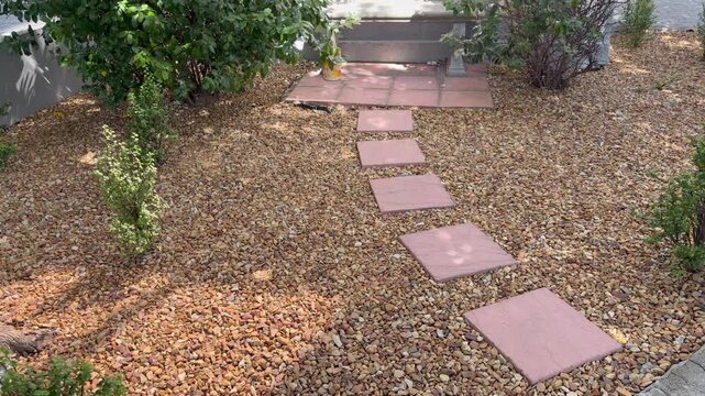 A cement and stone landscaped path in a small back garden.