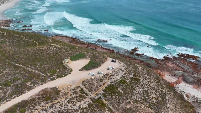 Aerial establishing of coastal track and turquoise ocean near Salmon Hole at Daly Head, camper vans gathered at top looking out to waves