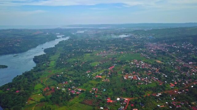 Aerial view capturing the powerful flowing waters of the River Nile curving through the lush green landscape and scattered settlements near Jinja, Uganda