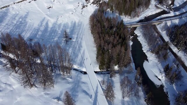 Aerial drone footage of ski slopes with people skiing in the Swiss Alps. Winter sports action, snowy mountains and alpine scenery in the Goms region, Valais, Switzerland.