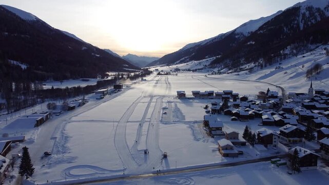 Aerial drone footage of ski paths with people skiing in the Swiss Alps. Winter sports action, snowy mountains and alpine scenery in the Goms region, Valais, Switzerland.