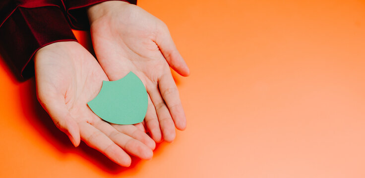 Protection concept. Green shield symbol hands holding orange background protection concept safety icon human palms security sign isolated object flat design