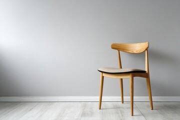 A light wood chair with a cushion sits against a grey wall.