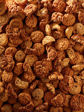 Batches of cookies are mixed together on a flat surface. The cookies show different shapes and textures. Natural light highlights the details of the cookies