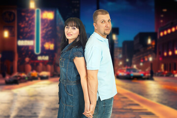 A man and a woman are standing on a city street, holding hands