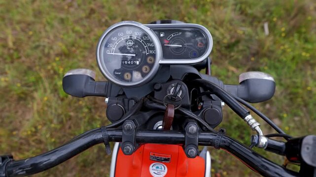 Close-up b-roll shows a motorcycle ignition key being turned on, with the speedometer and handlebars visible in the Cambodia countryside