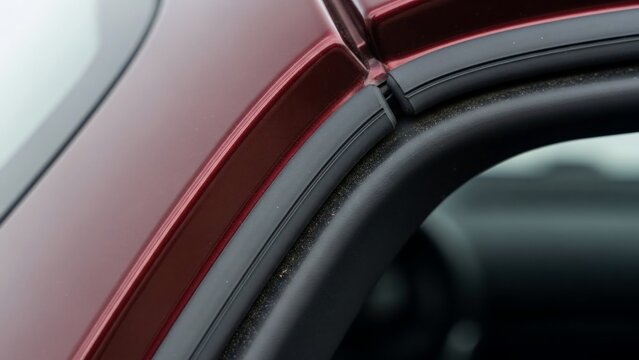 Close-up of a red car door frame and window seal.