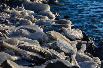 Obraz premium Bizarre ice formations and icicles on the rocky lake shore during freezing winter.
