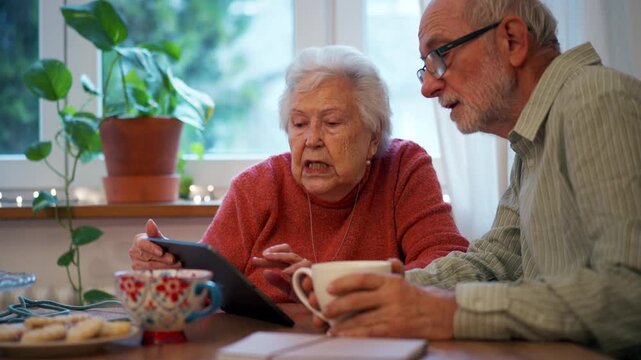 Senior man and woman making reservation online, using tablet.