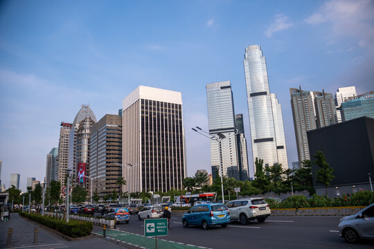 Jakarta, Indonesia - March 12, 2024 : Vehicles travel along Sudirman Avenue in central business district. Modern glass skyscrapers and high-rise offices line the city skyline under a clear sky.