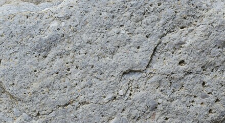 Naklejka premium Detailed close-up of a rugged, light gray natural stone surface, showcasing its unique granular texture and subtle fissures, capturing the raw beauty of natural rock