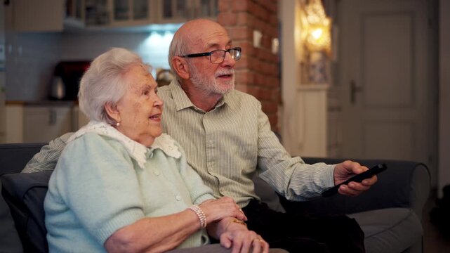 Lovely senior couple watching television in the evening.
