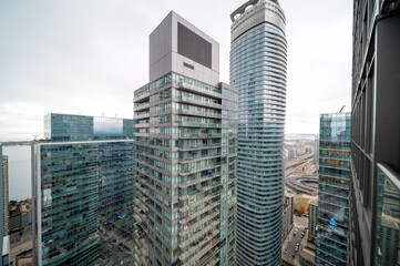 Naklejka premium Urban toronto skyline featuring contemporary residential and commercial skyscrapers with glass facades, reflecting the cloudy sky over the city and waterfront. In mimco