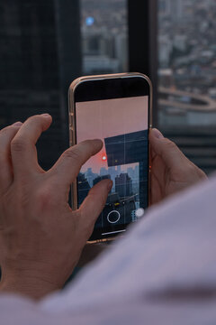 Person photographing or taking video of city skyline at sunset with smartphone