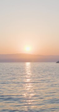 Sonnenaufgang &uuml;ber ruhiger Meeresfl&auml;che mit klarer Horizontlinie, erste Sonnenstrahlen steigen langsam aus dem Wasser auf, sanfte Farbverl&auml;ufe am Himmel und stille Morgenstimmung &uuml;ber dem Meer
