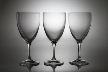 Fototapeta premium Three empty wine glasses isolated on light background. Minimalist glassware set for restaurant, bar, wine tasting, celebration, menu design