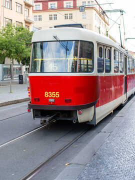 A classic red tram car crossing through a European city center