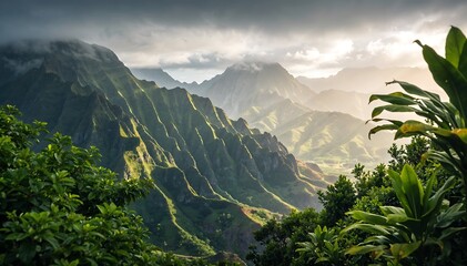 A dramatic landscape of lush green mountains and valleys in Hawaii, with tropical foliage in the foreground and a cloudy sky with sunlight peeking through.